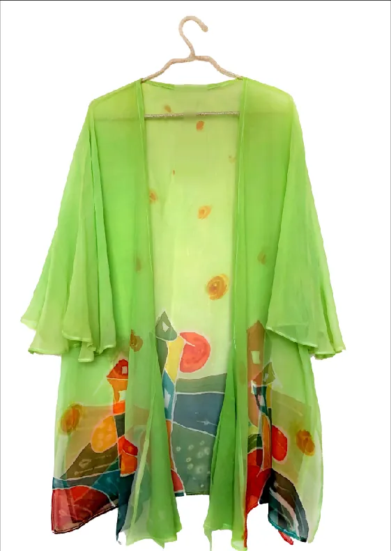 A sheer lime-green kimono on a hanger, scattered with small orange suns and painted with colorful houses and hills near the hem.